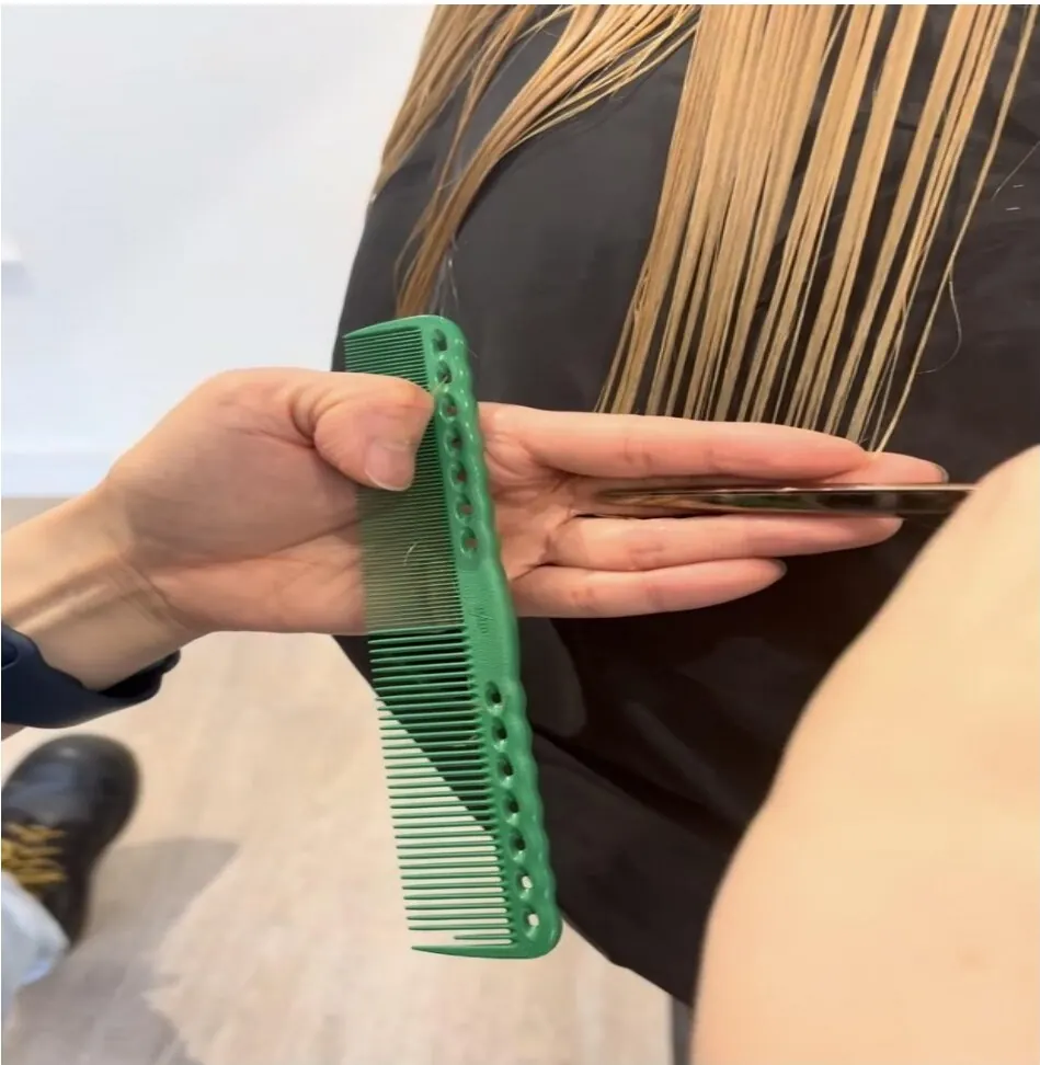 Stylist trimming hair with scissors and a green comb at Haku Blackrock